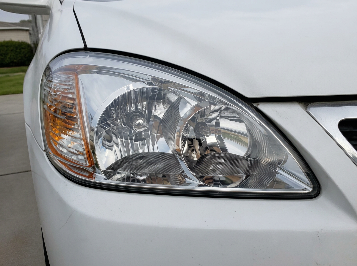 The same white sedan headlight after restoration, crisp and transparent