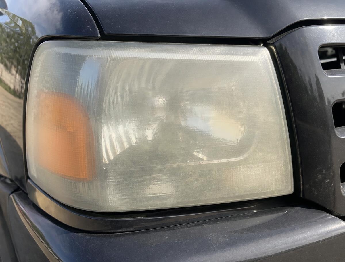 Black pickup truck headlight before restoration, milky and oxidized