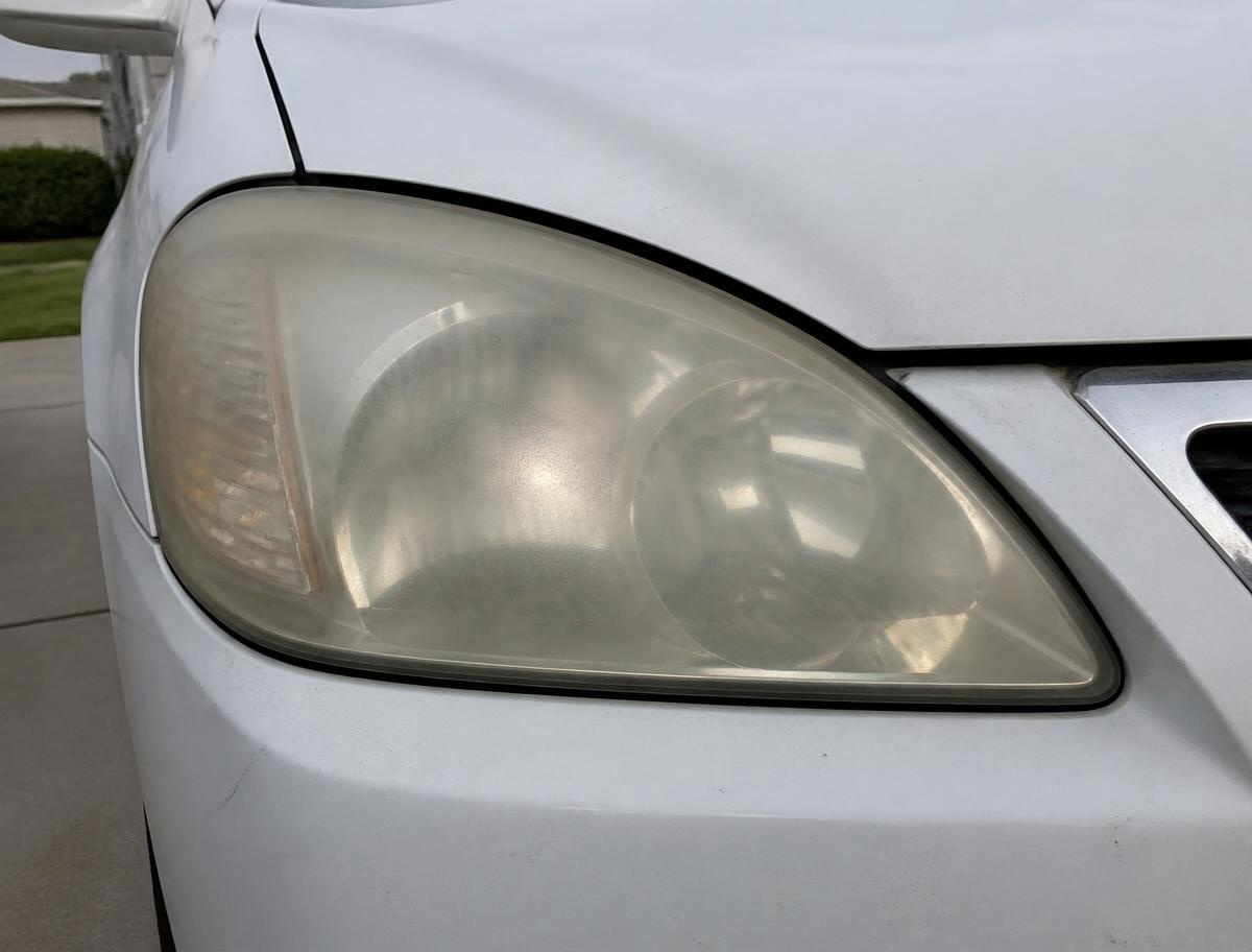 White sedan headlight before restoration, yellowed and foggy